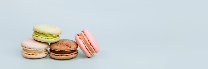 Sweet macaroons in pastel colors isolated on blue background. Delicious beautiful macaroons. Banner for website header design with copy space.