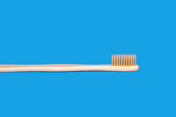 Ecological bamboo toothbrush on a blue background. Wooden toothbrush without plastic. Waste-free personal care products, dental care concept
