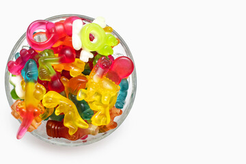 A large pile of multi-colored jelly gummy candies in a glass bowl on a white background. Variety of...