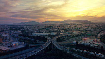 Obraz premium Aerial drone photo of modern Attiki Odos toll multilevel interchange highway with National road in Attica area at sunset, Athens, Greece