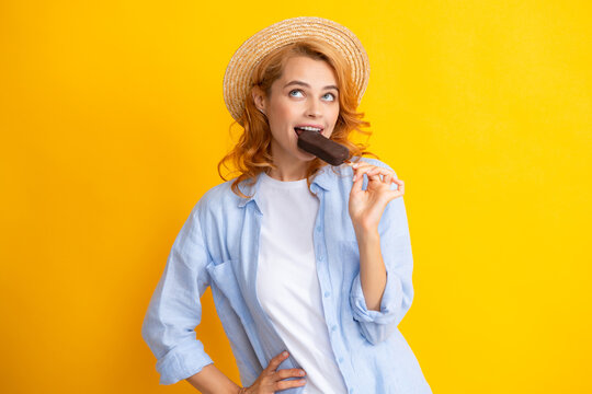 Portrait of redhead girl with chocolate ice cream on yellow background. Curly cheerful woman eating ice cream.