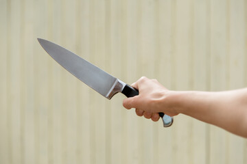 sharp dangerous knife in a female hand on a yellow background. Self defense, fear, horror, murder