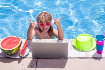 Child with laptop in swimming pool in summer day. Work outside concept, Business and summer.
