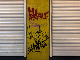 İzmir, Konak  Turkey - 12 22 2022:  Graffiti made in red and black colors on the yellow wall of the closed store, night shoot, background texture. Protest drawing on street, hip hop, rap culture