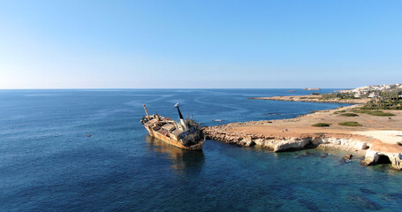 Flying drone over the coastline of the island overlooking an old rusty sunken ship or liner, rocky...
