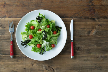 Plate with assorted vegetable salad on white plate on wooden background. Copy space.