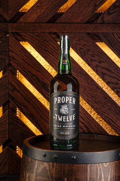 Bottle of Irish whiskey Proper No. Twelve on wooden barrel against glowing wall
