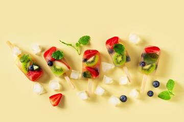 Fruit ice cream, colorful summer dessert on stick with strawberry, blueberry, kiwi and mint leaf