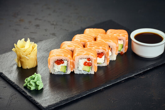 Sushi roll (Philadelphia) with salmon, red caviar, avocado, cream cheese on dark background. Sushi menu. Japanese food.