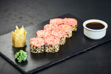Baked rolls with sesame seeds and cap of crab, cream cheese and tobiko flying fish roe on dark background. Sushi menu. Japanese food.