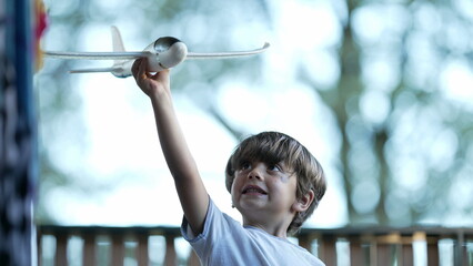 One happy small boy throwing foam toy airplane. Child playing with large plane