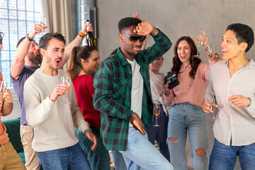 Multiracial friends dancing and drinking wine at birthday party at home