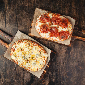 Two Roman-style pizzas with cheese and jamon serrano. Roman square pizza or Pinsa on thick dough, Italian cuisine