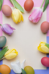 Tulip flowers and decorative Easter eggs on blank paper background with copy space