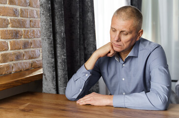 Obraz premium Portrait of a pensive middle-aged man sitting at a table.