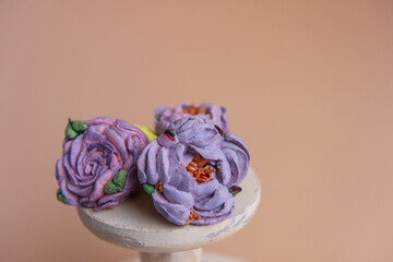 On wooden round background lie natural marshmallows in the form of purple peony flowers.