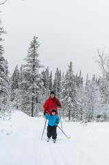 Young cross country skier in front of mother