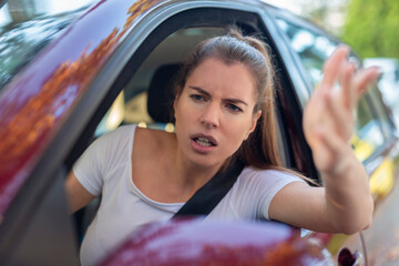 Stressed angry woman in driver's seat of modern car, view through windshield