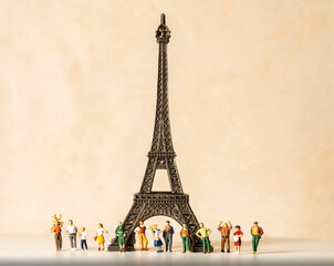 Miniature people underneath the Eiffel tower.  Travel icon and world renowned landmark concept.
