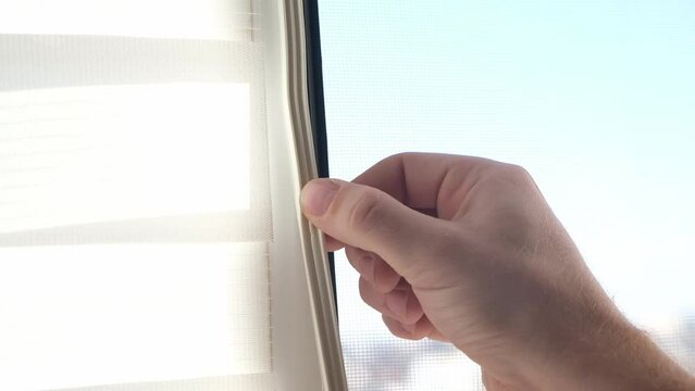 The man wipes the window frame with a degreaser and glues a sealing rubber tape on it for noise insulation, wind protection, weather protection.