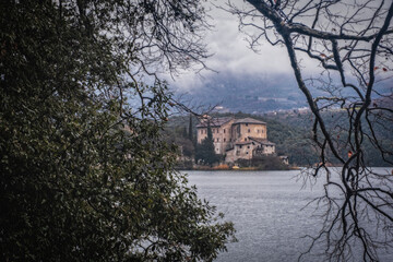 Beautiful view of the castle on the shores of Lake Toblino, Trentino, Italy. Cloudy day in January 2023