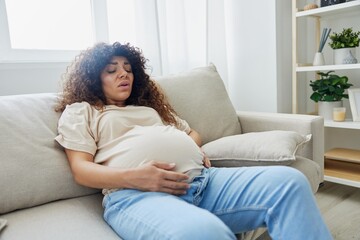 Pregnant woman lies on the couch at home headache, pregnancy and motherhood difficulties, severe fatigue, headache