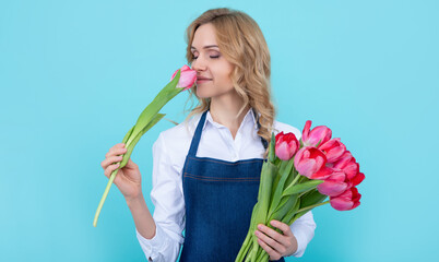 girl smile in apron with spring tulip flowers on blue background