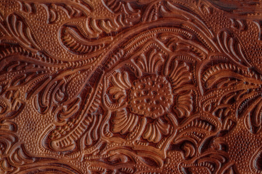 Dark brown red old cracked  leather with floral print. Sample of rough leather with ornament.