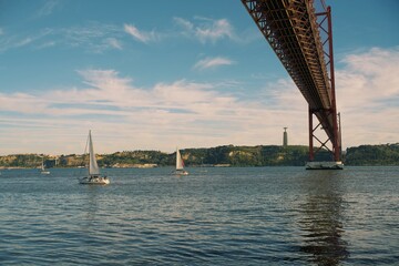 April 25 Bridge on the Tagus River in Lisbon, Portugal. In the background is a statue of Jesus Christ.