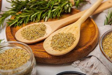 Dried rosemary in wooden spoons and bowl, branches of fresh rosemary on white texture background.Spices and herbs for meat and fish.Recipe.Culinary concept.Organic herbs. Place for text.