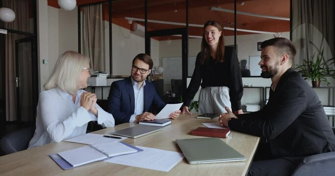 Laughing positive office employees and mature businesslady boss lead pleasant, friendly conversation, working on project, share opinion and creative ideas feel satisfied with teamwork in board room