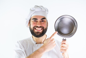 Young male chef showing a stainless saucepan while smiling and looking at camera. Isolated on a white background