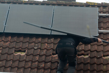 Installing of solar panels on roof in cloudy winter day, green energy in Europe