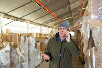 Male warehouse worker talking on a cell phone