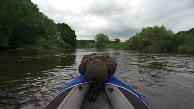 Canoe POV floating down a river with a large green bergen backpack