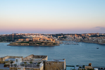 Sunset in Valetta with a view on The Three Cities. View on the city and the sea from a rooftop terrace