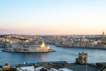 Fototapeta premium Sunset in Valetta with a view on The Three Cities. View on the city and the sea from a rooftop terrace