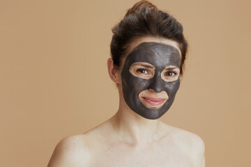 young female with cosmetic mask against beige background
