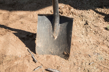 Shovel stuck in sandy soil closeup in sunny day