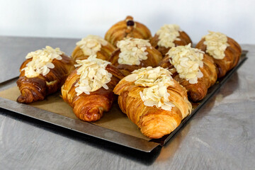 A tray full of almond-flavored croissants in a bakery