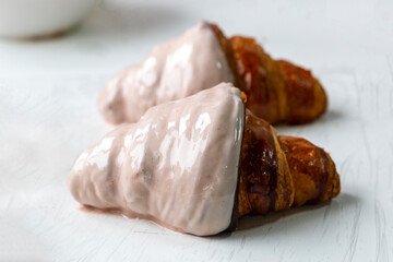 Rows of croissants are half covered with white chocolate in a bakery. Pastry decoration