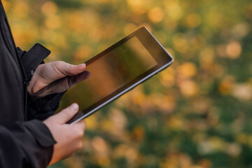 close-up boy with tablet near school with online learning book, tablet in child's hands, schoolgirl, on beautiful yellow-green background, blurred background behind, bokeh, online education, side