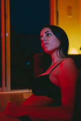Sensual young latin woman in underwear with a red light pointing at her. Vertical photo.