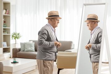 Naklejka na ściany i meble Elderly man getting dressed in front of a mirror