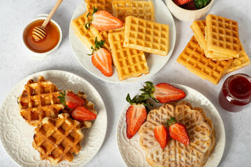 Belgian waffles set with honey and strawberries white wooden