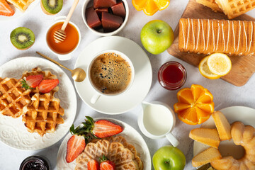 happy and hearty breakfast with waffles, buns, fresh fruits and berries with jam and honey. perfect breakfast