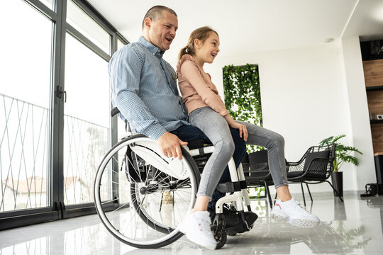 A father, facing physical challenges, engages in lively play with his daughter in the living room, creating cherished moments of joy and togetherness.