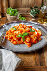 Italian Gnocchi with tomato sauce and basil on wooden background