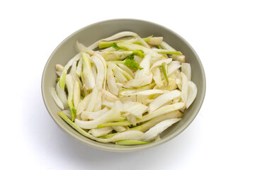 Sliced fresh fennel in bowl on yellow background.