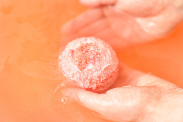 Fototapeta premium Woman putting bath bomb into water in room, closeup